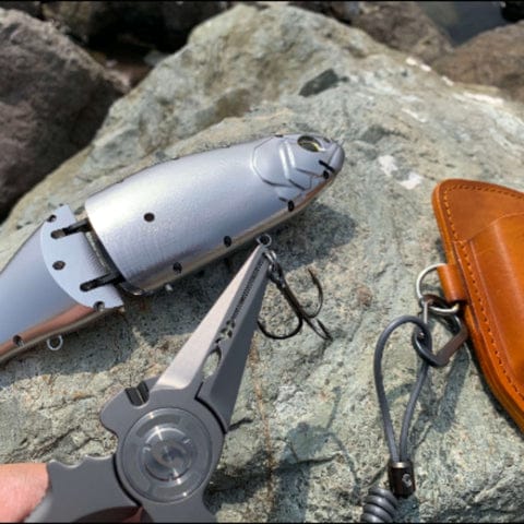Pliers and lure on stone background.